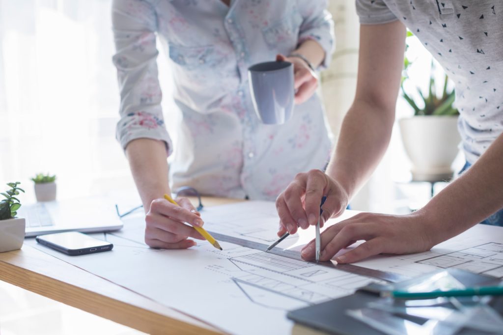 Free photo close-up of architecture hands working on blueprint over wooden table at office