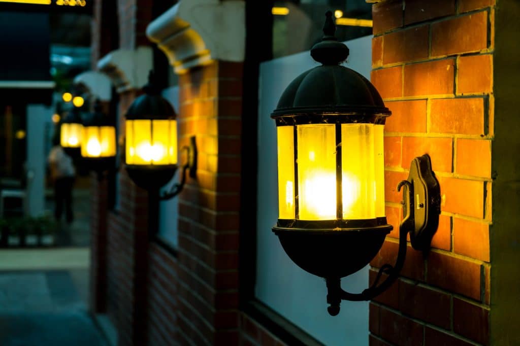 Lamp against a red brick wall at night.